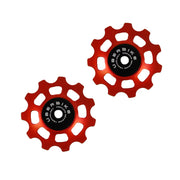 two orange ceramic 11 tooth jockey wheels on a white background