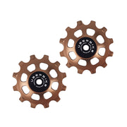 two bronze ceramic 12 tooth jockey wheels on a white background
