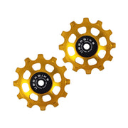 two gold ceramic 12 tooth jockey wheels on a white background