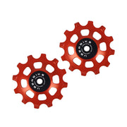 two orange ceramic 12 tooth jockey wheels on a white background