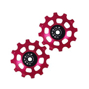 two red ceramic 12 tooth jockey wheels on a white background