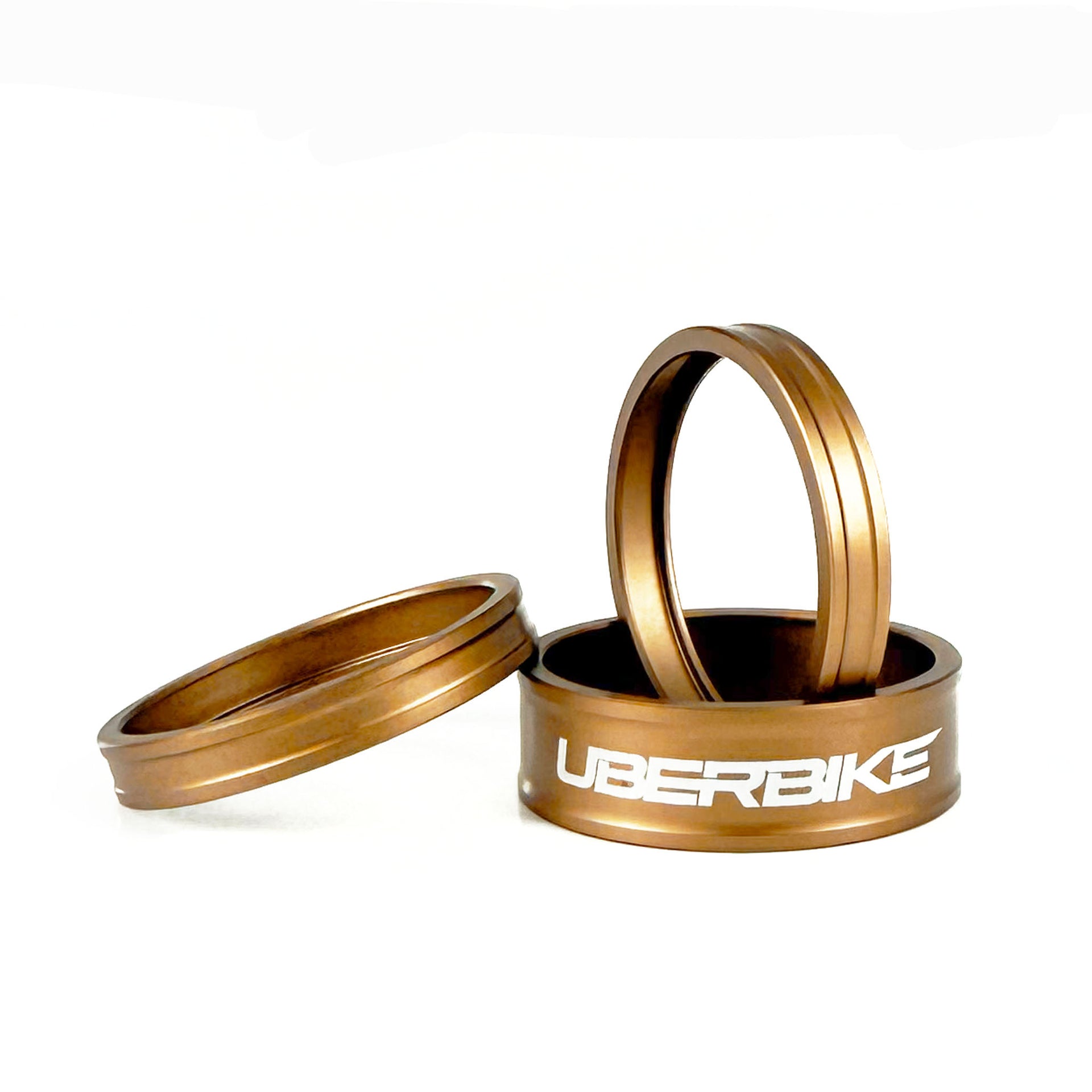 A set of headset spacers in bronze with uberbike branding stacked on a white background