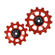 one ceramic orange 12 tooth and one 14 tooth jockey wheel on a white background