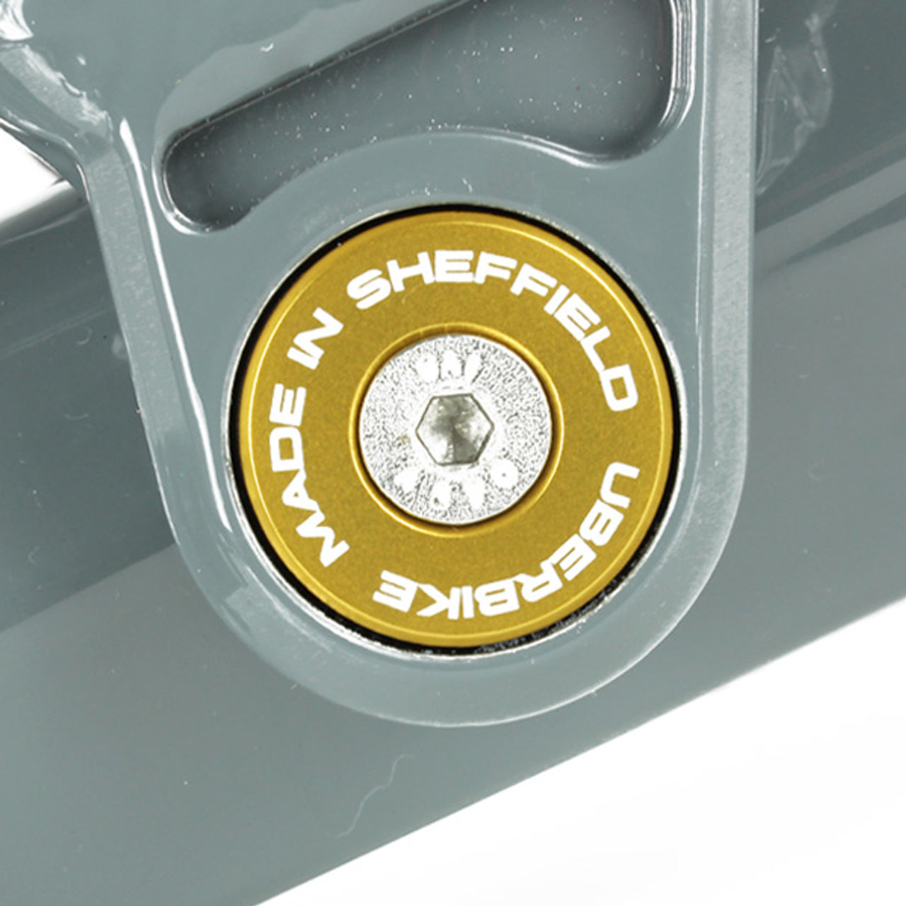 Close-up of a gold 'Uberbike Made in Sheffield' Pivot bearing cap in a bike frame