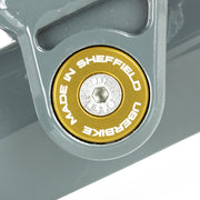 Close-up of a gold 'Uberbike Made in Sheffield' Pivot bearing cap on a metallic surface.