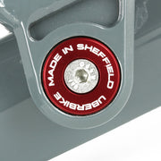 Close-up of a Red 'Uberbike Made in Sheffield' Pivot bearing cap on a metallic surface.