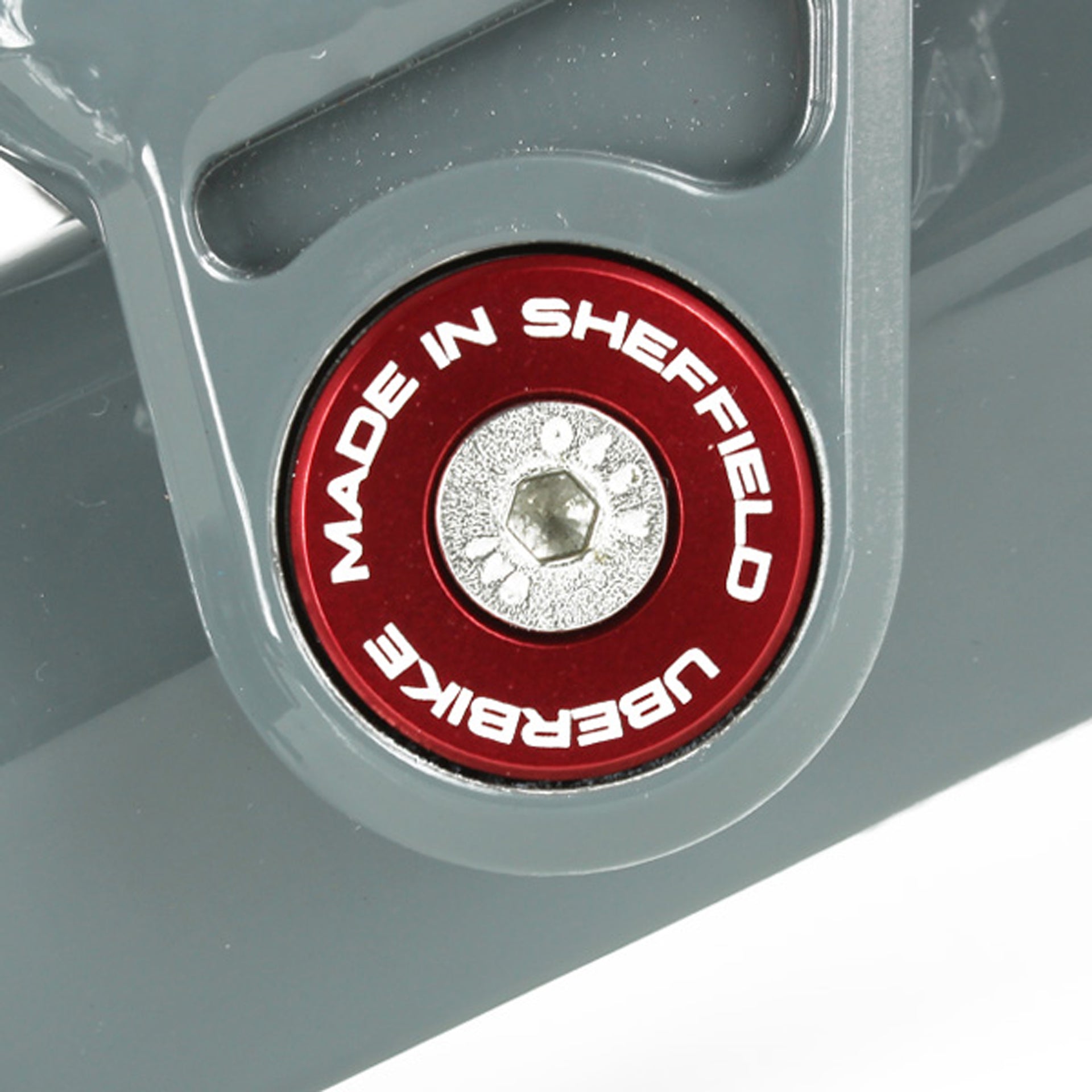Close-up of a Red 'Uberbike Made in Sheffield' Pivot bearing cap on a metallic surface.