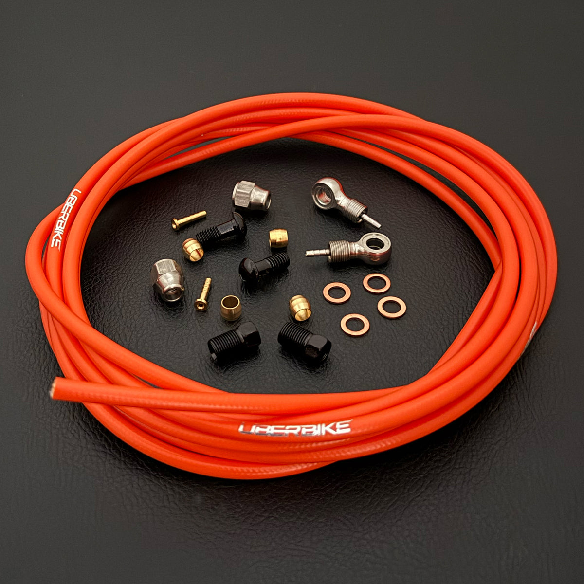 SRAM XX hydraulic orange brake hose kit with silver banjo fittings and Uberbike branding on a black background
