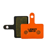 Orange Shimano Cues U6030 brake pad with Uberbike branding on a white background