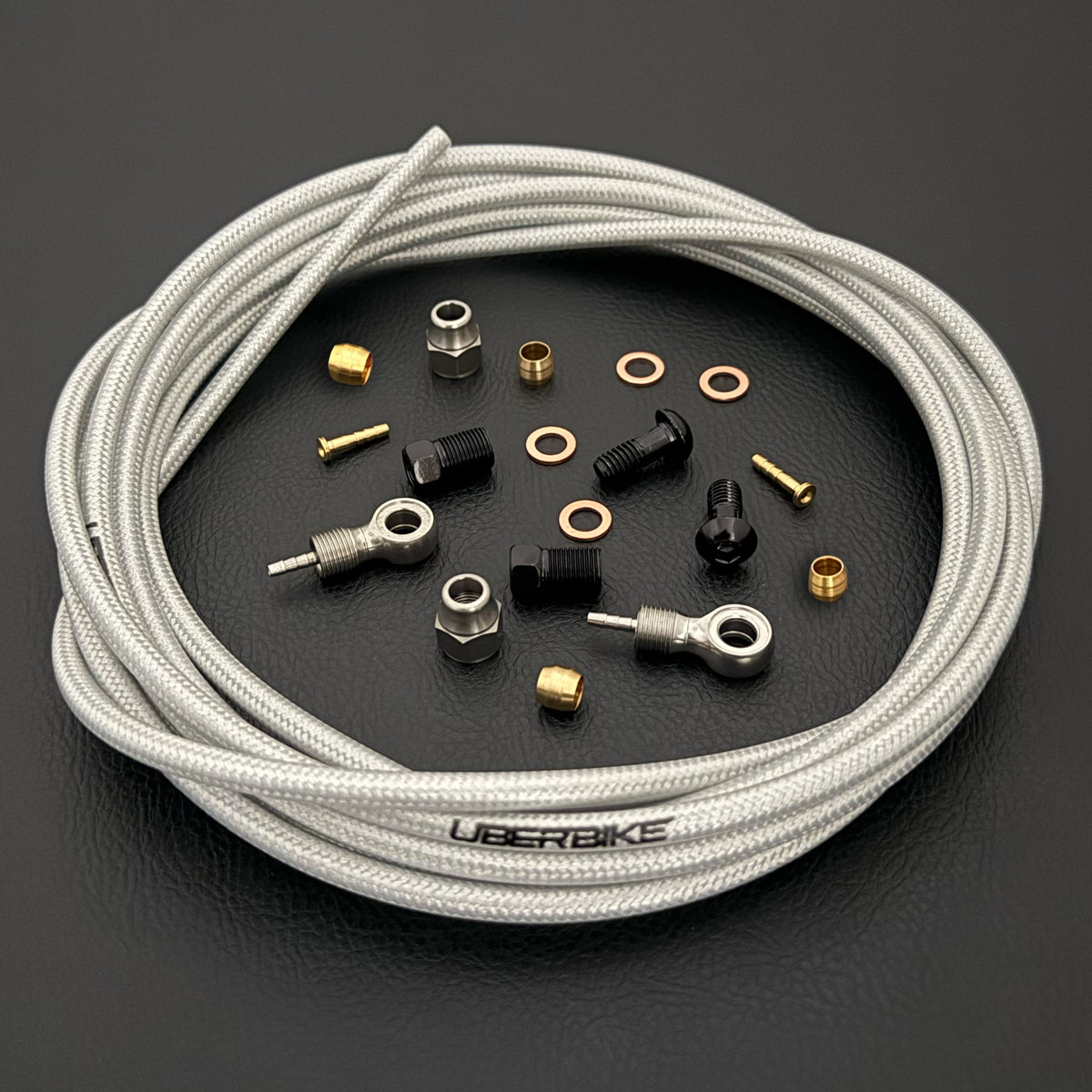 Shimano saint / zee raw silver braid kevlar hydraulic brake hose kit with banjo fittings and Uberbike branding on a black background