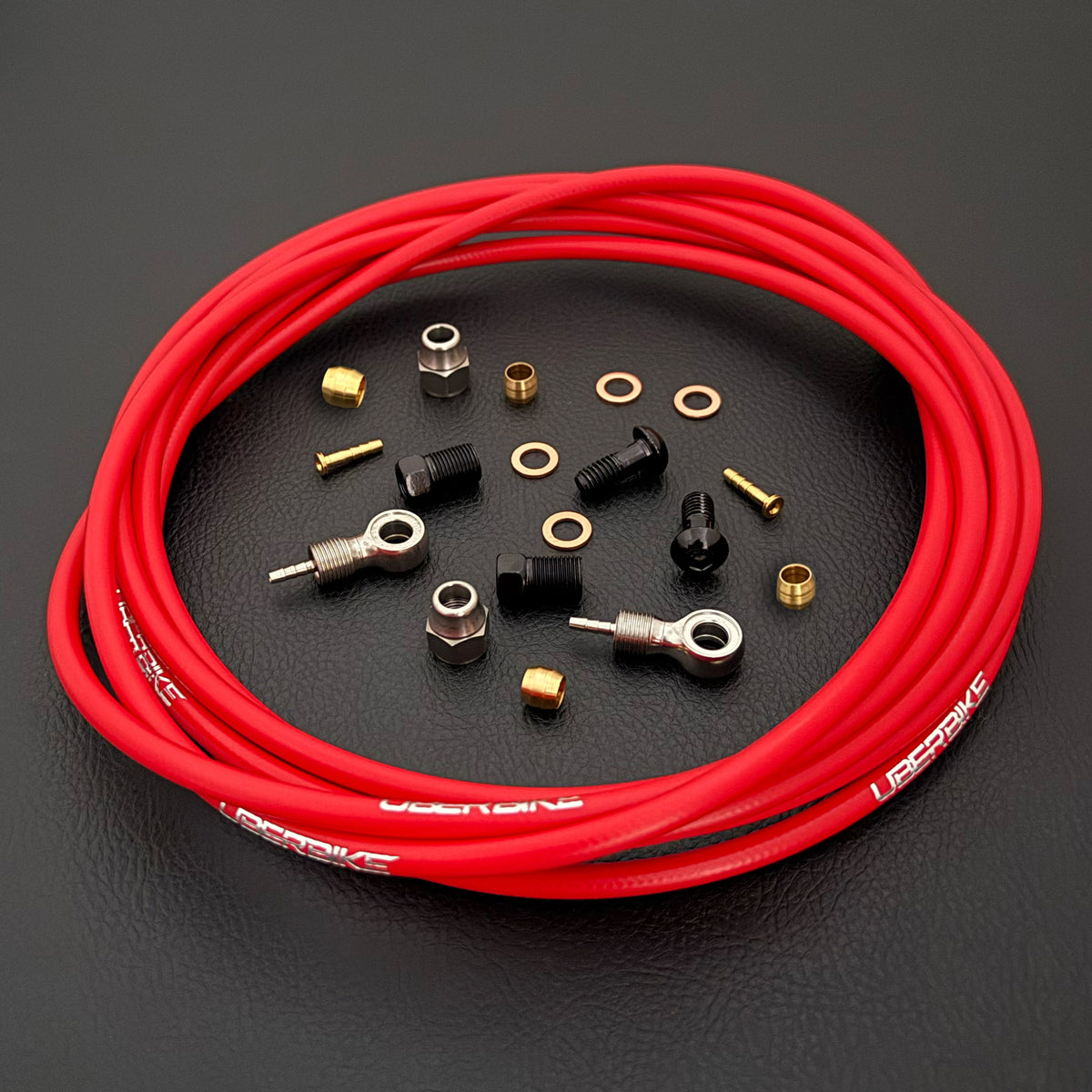 Shimano saint / zee red kevlar hydraulic brake hose kit with banjo fittings and Uberbike branding on a black background