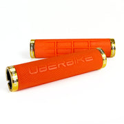 two orange fat grip mountain bike grips and gold lockrings on a white background