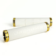 two white fat grip mountain  bike grips and gold lockrings on a white background