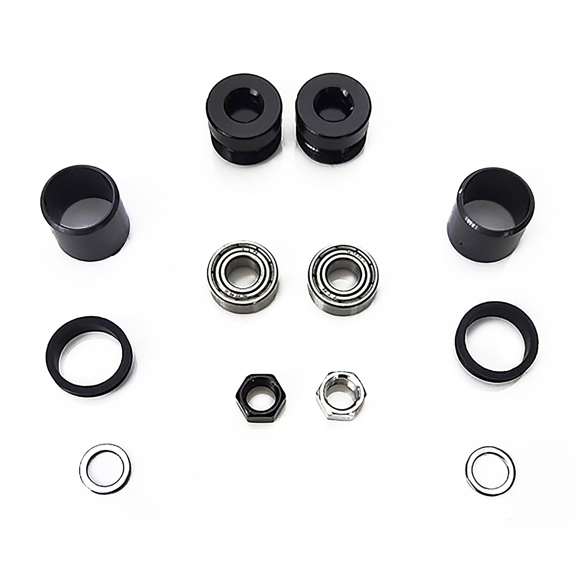 Set of bicycle components including black bushings and metal bearings on a white background